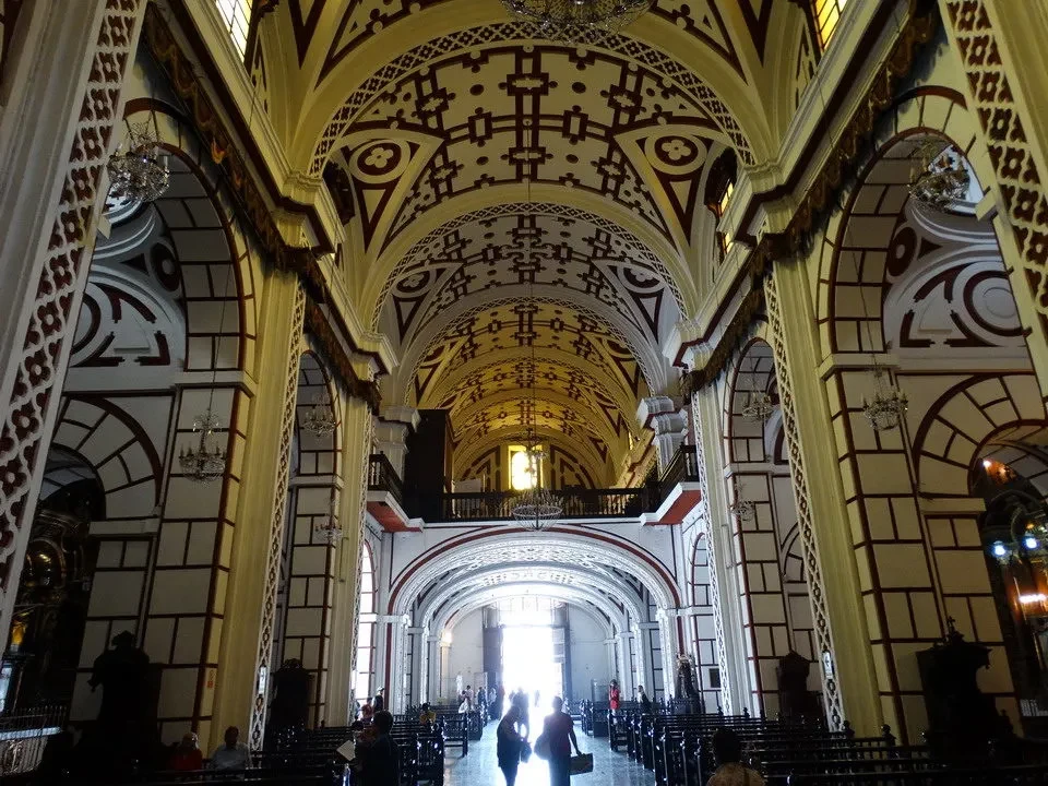 Interno maestoso di una chiesa con volte elaborate e colonne in un corridoio lungo.