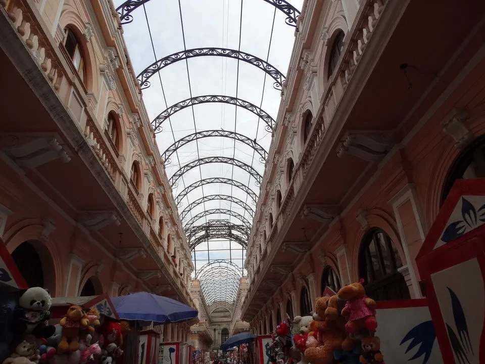 Una galleria coperta con archi decorativi si estende lungo una strada in Perù o Bolivia.