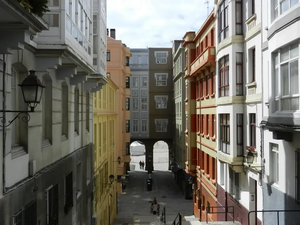 Una stretta via storica fiancheggiata da edifici colorati e un ponte in lontananza.