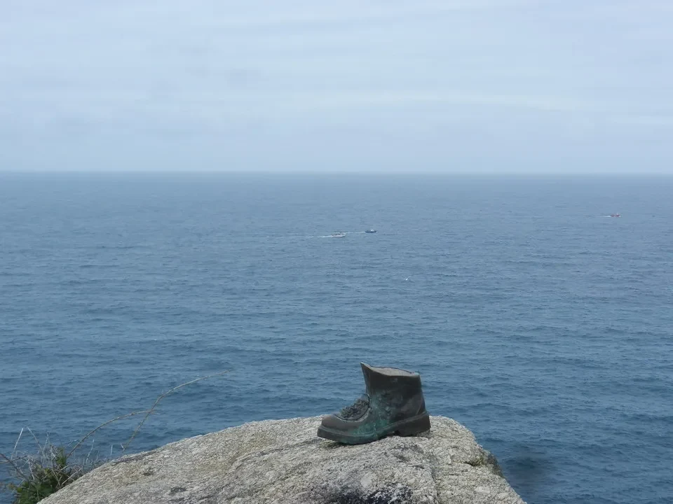 Un vecchio stivale è posato su una roccia sopra il mare.