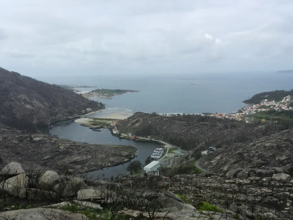 Panorama costiero roccioso con un fiume che si snoda tra le colline portoghesi e il mare.