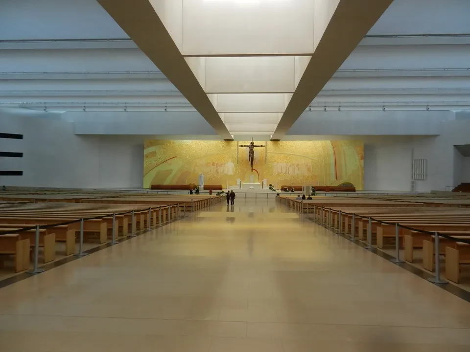 Interno di una chiesa con file di sedie rivolte verso un altare decorato.