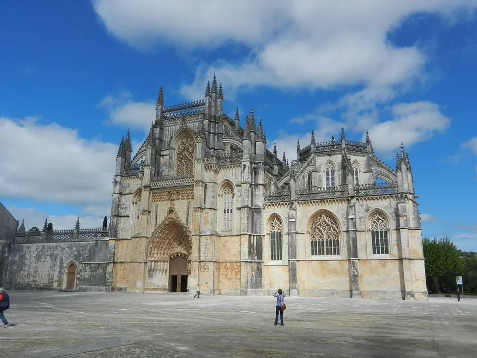 Mosteiro da Batalha in Portugal is shown under a bright sky.