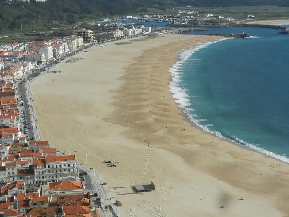 Una vista panoramica della spiaggia di Nazaré con edifici e acqua cristallina.