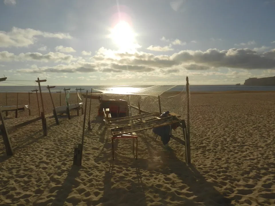Una spiaggia sabbiosa con una rete da pesca allestita sotto il sole.
