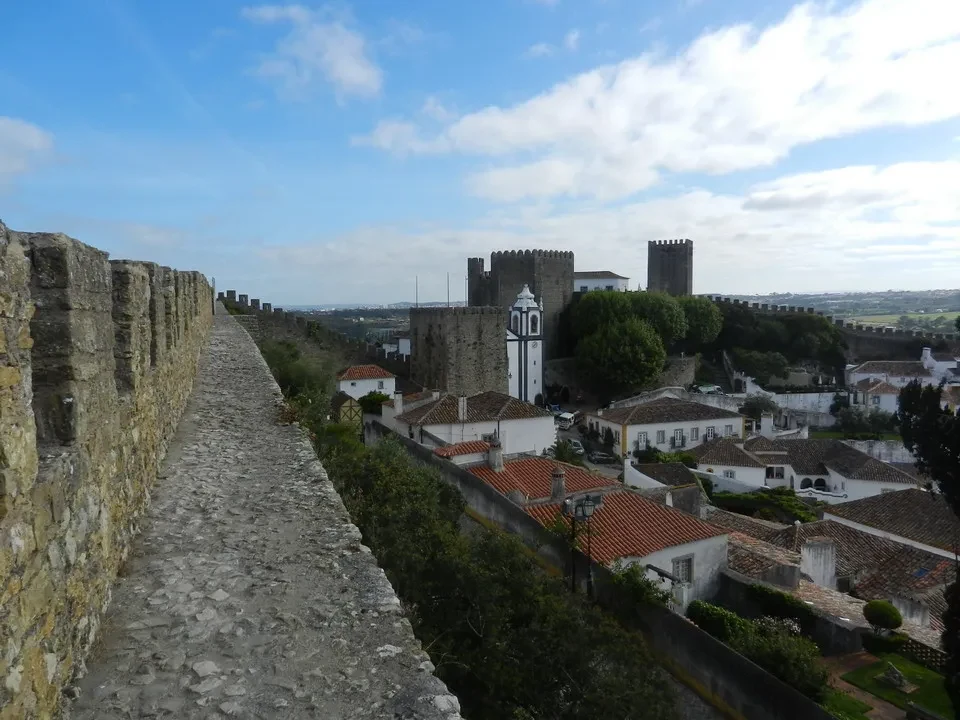 Muro di pietra che costeggia una collina con una vista panoramica sulla città storica.