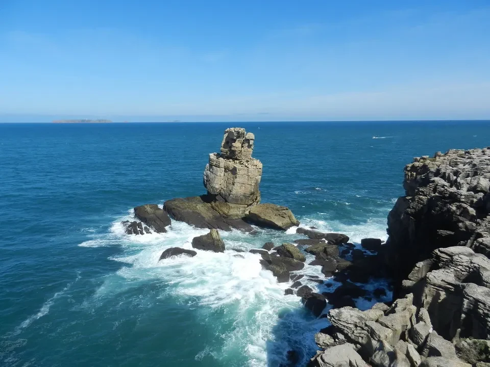 Una scogliera rocciosa si erge dal mare sotto un cielo azzurro. Una scogliera rocciosa si erge dal mare sotto un cielo azzurro.