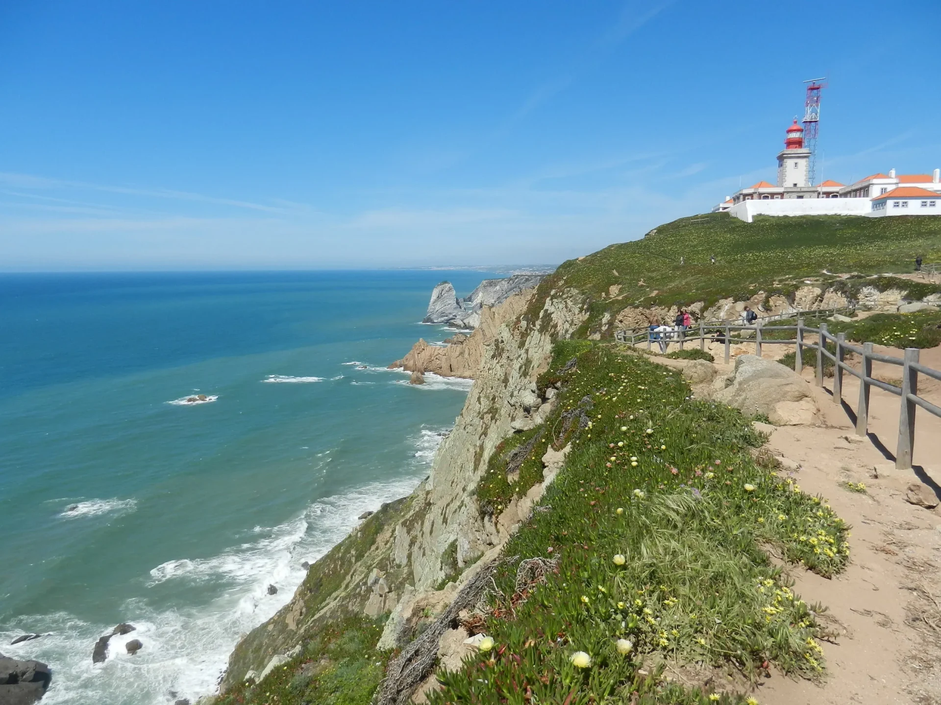 Una vista panoramica della costa rocciosa con un faro bianco in Portogallo.
