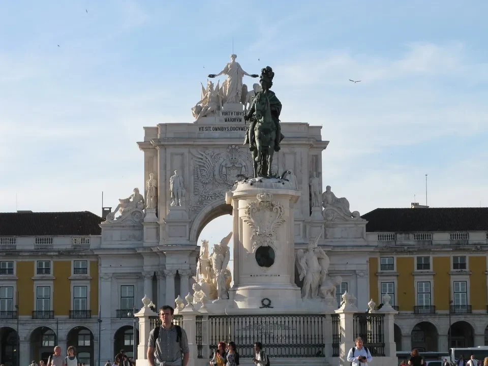 Una veduta della Praca do Comércio a Lisbona con una statua in bronzo in primo piano.