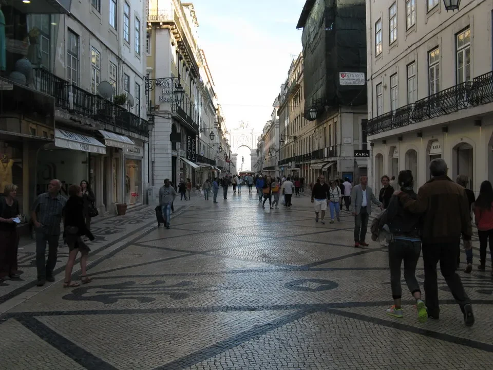 Una veduta di una strada pedonale in pietra a Lisbona con edifici storici ai lati.