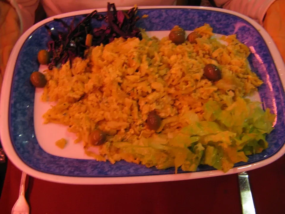 Un piatto di cibo con verdure e olive è presentato su un piatto blu.