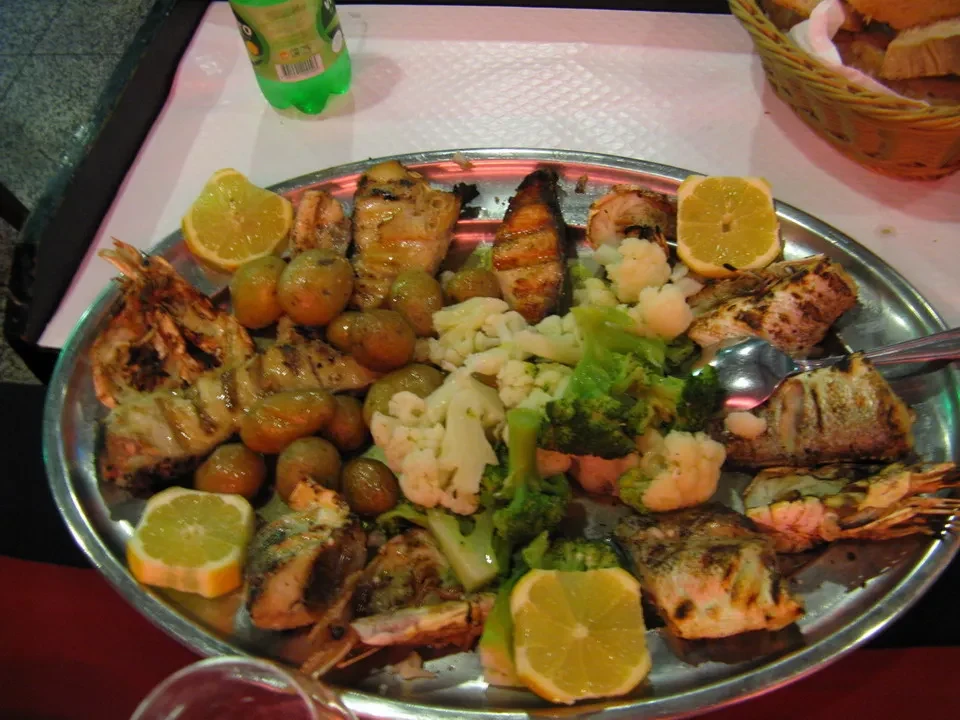 Un misto di pesce grigliato con contorni di verdure e limoni in un ristorante portoghese.