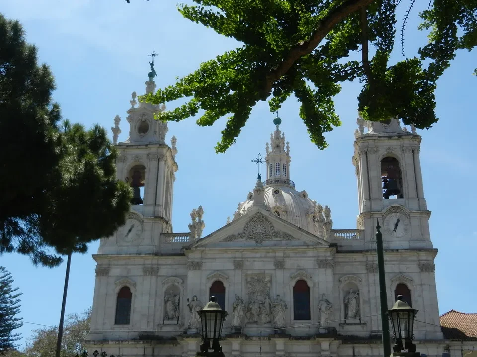 Vista della Basilica da Estrela con alberi frondosi in primo piano.
