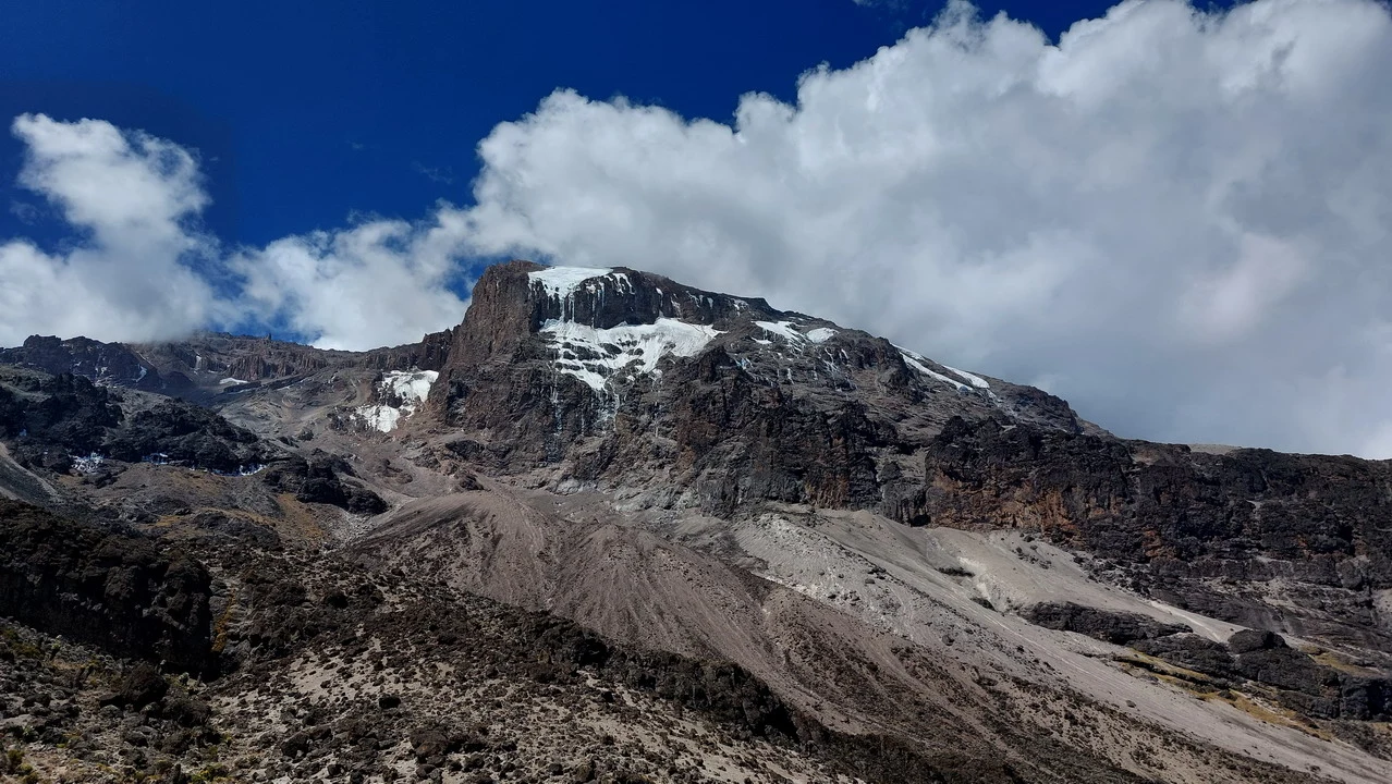 Una torre lavica si estende attraverso un paesaggio montano con nuvole basse.