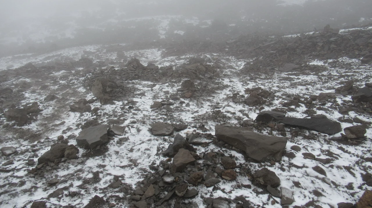 Paesaggio montano coperto di neve con rocce in primo piano.