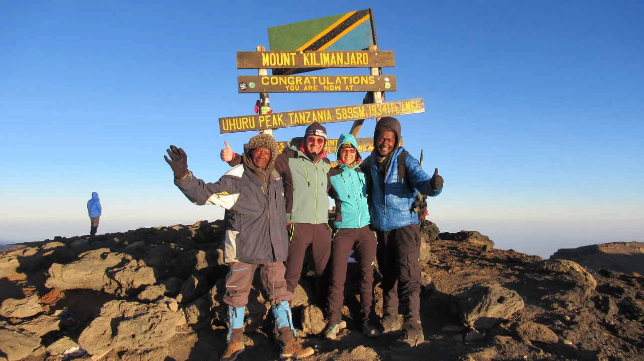 Gruppo di persone in cima al Monte Kilimanjaro con vista panoramica.