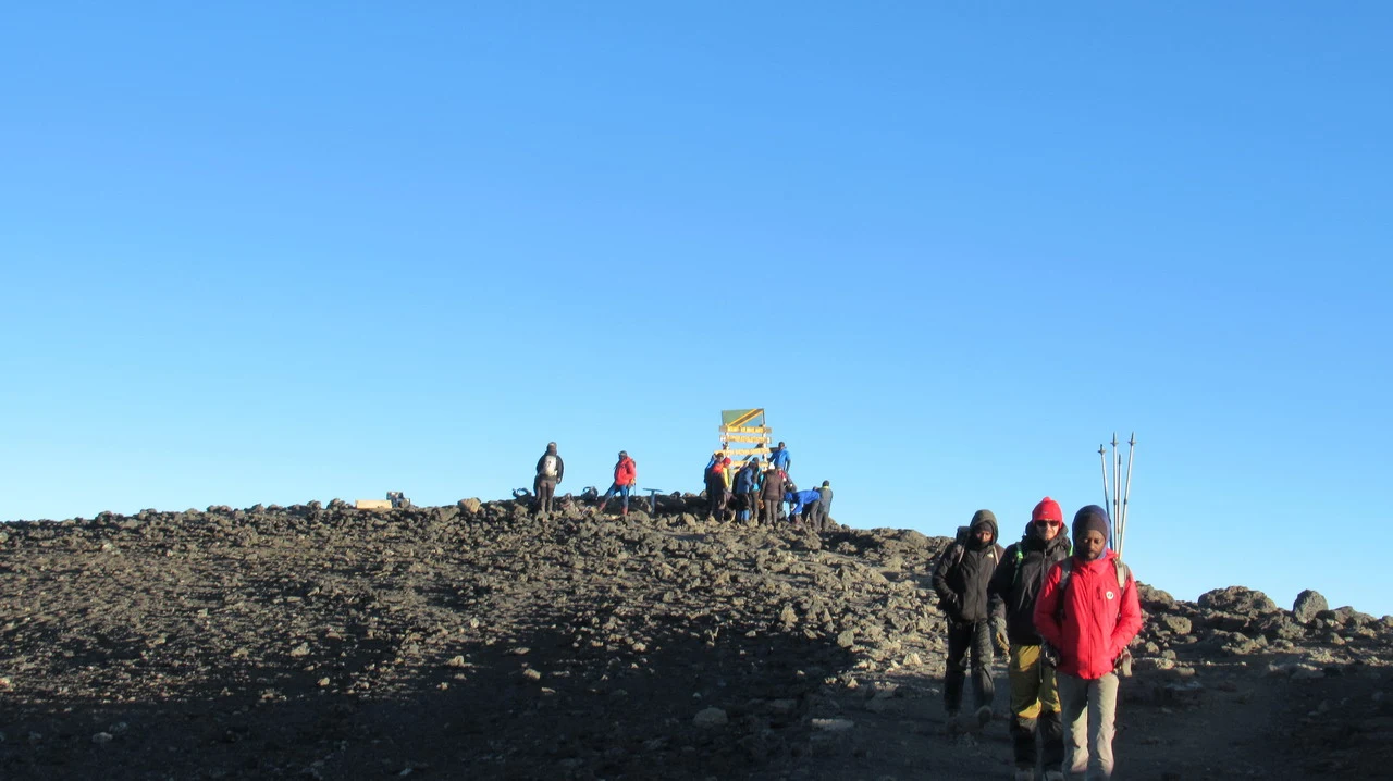 Un gruppo di persone si trova in cima a una cresta rocciosa con uno sfondo vasto. Un gruppo di persone si trova in cima a una cresta rocciosa con uno sfondo vasto.