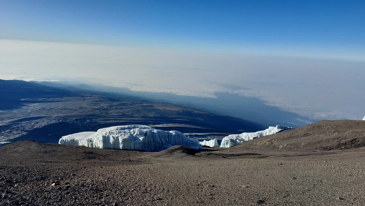 La cima del Kilimangiaro è visibile sopra un paesaggio vasto e montuoso.