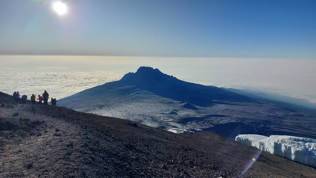 Un gruppo di escursionisti si trova sulla cresta rocciosa con una vista ampia sul paesaggio.
