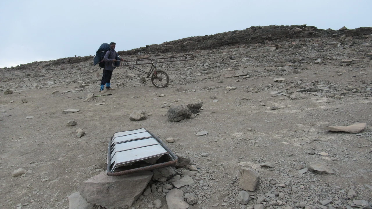 Una persona spinge una carrozza su un terreno roccioso in Tanzania.