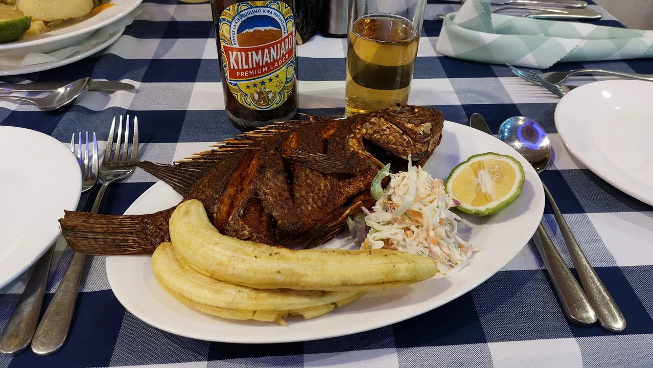 Pesce alla griglia con patate e accompagnamenti a cena in Tanzania.