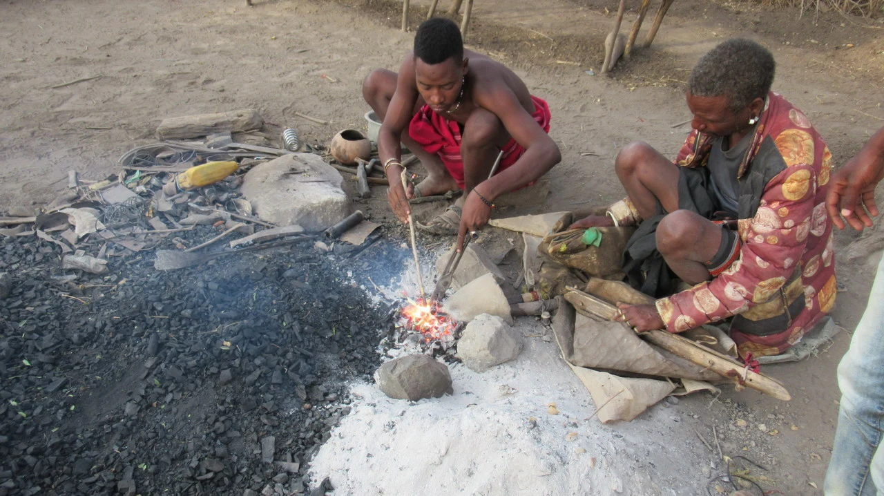 Uomini preparano un fuoco all'aperto in un villaggio della Tanzania durante una safari.