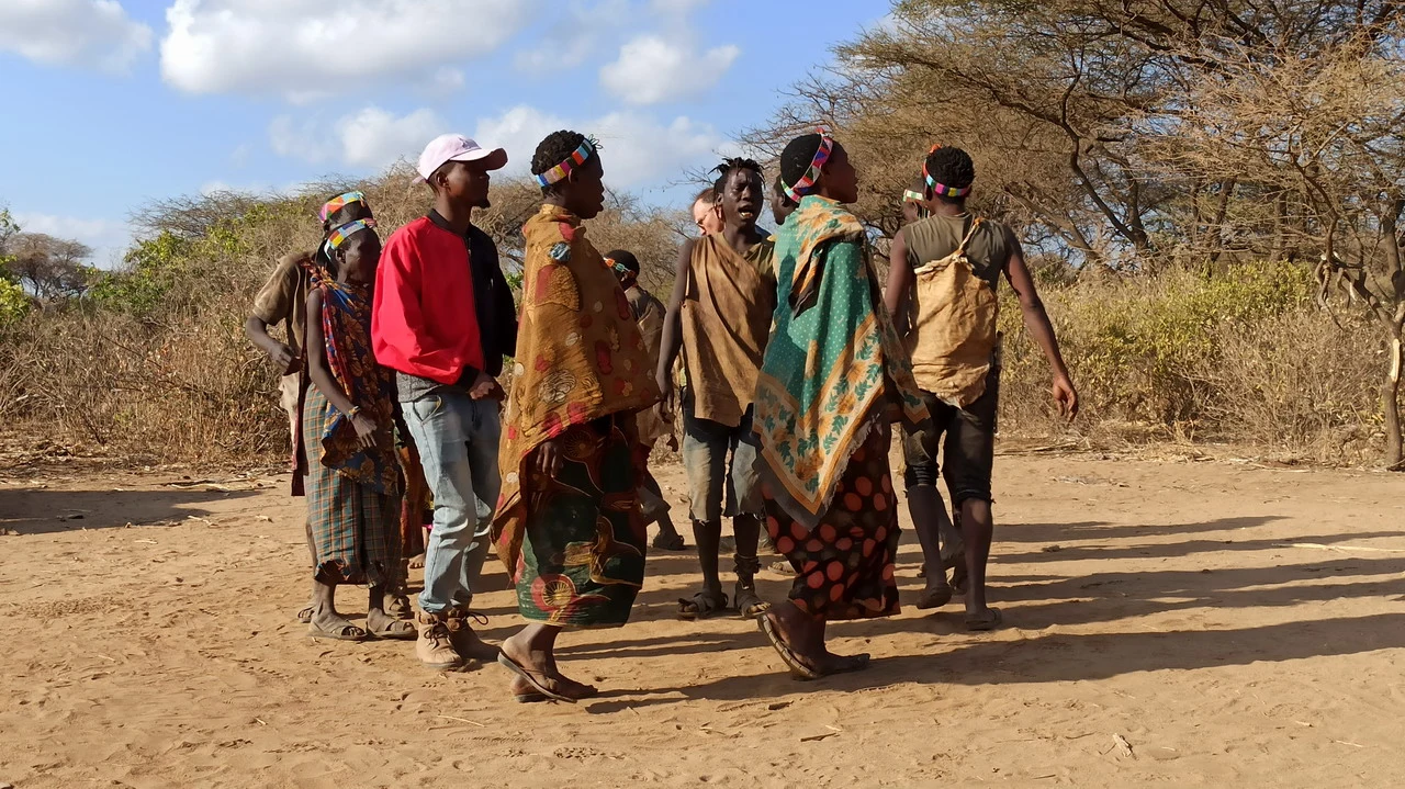 Un gruppo di persone cammina attraverso un paesaggio secco in Tanzania.