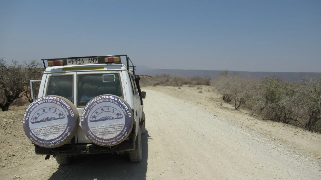 Un veicolo fuoristrada percorre una strada sterrata nel paesaggio africano.