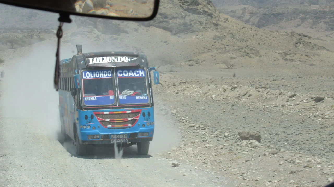 Un autobus viaggia su una strada polverosa nel paesaggio della Tanzania.