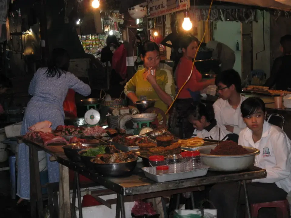 Mercato di Hanoi con venditori e cibo all'aperto.