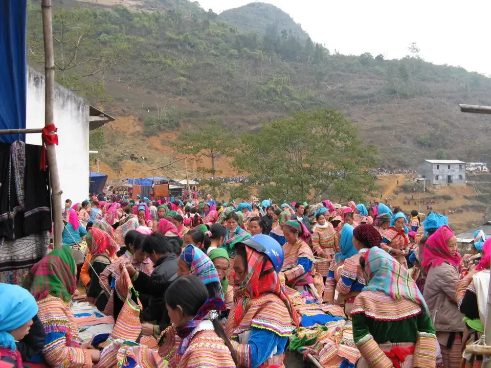 Un gruppo di persone con abiti tradizionali si radunano in un paesaggio collinare tra Vietnam e Cambogia.