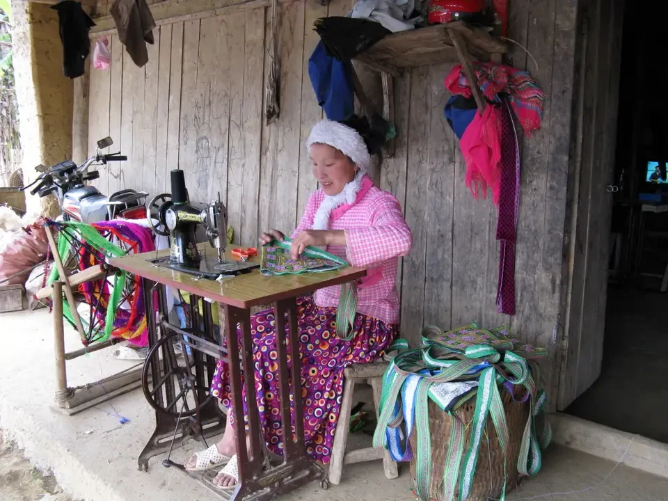 Una donna lavora su un tavolo all'aperto in un mercato vietnamita o cambogiano.
