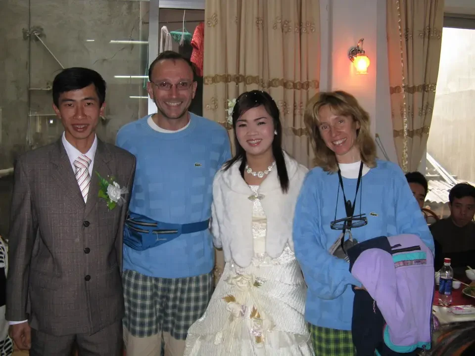 Un gruppo di persone sorride durante un matrimonio in un interno decorato.