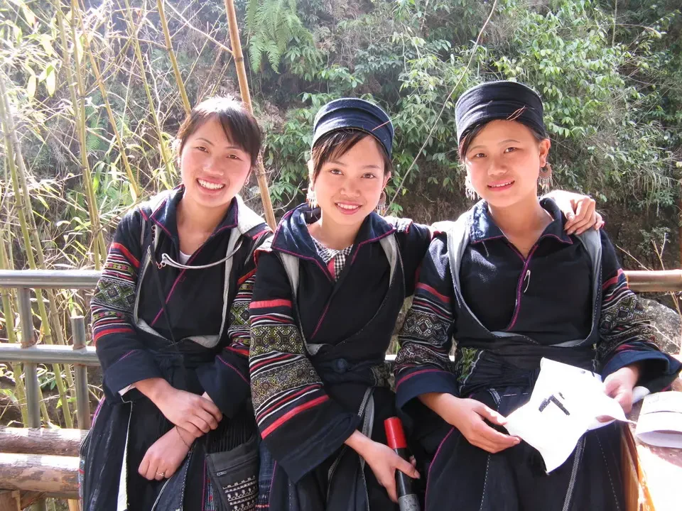 Tre donne sorridono in un paesaggio rurale tra Vietnam e Cambogia.