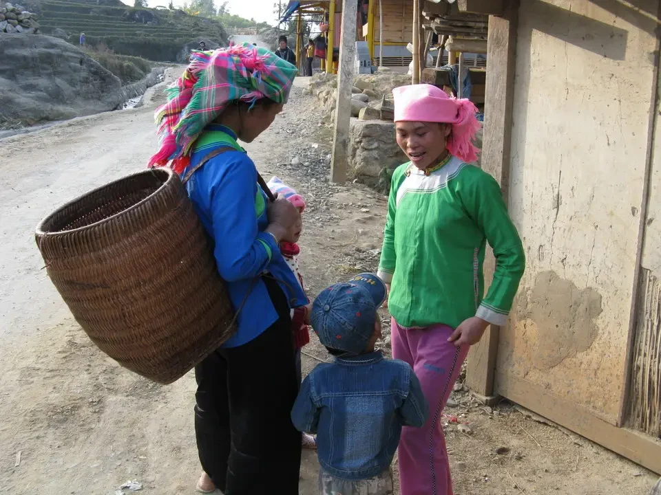Tre donne sorridono mentre camminano lungo una strada sterrata in Vietnam o Cambogia.