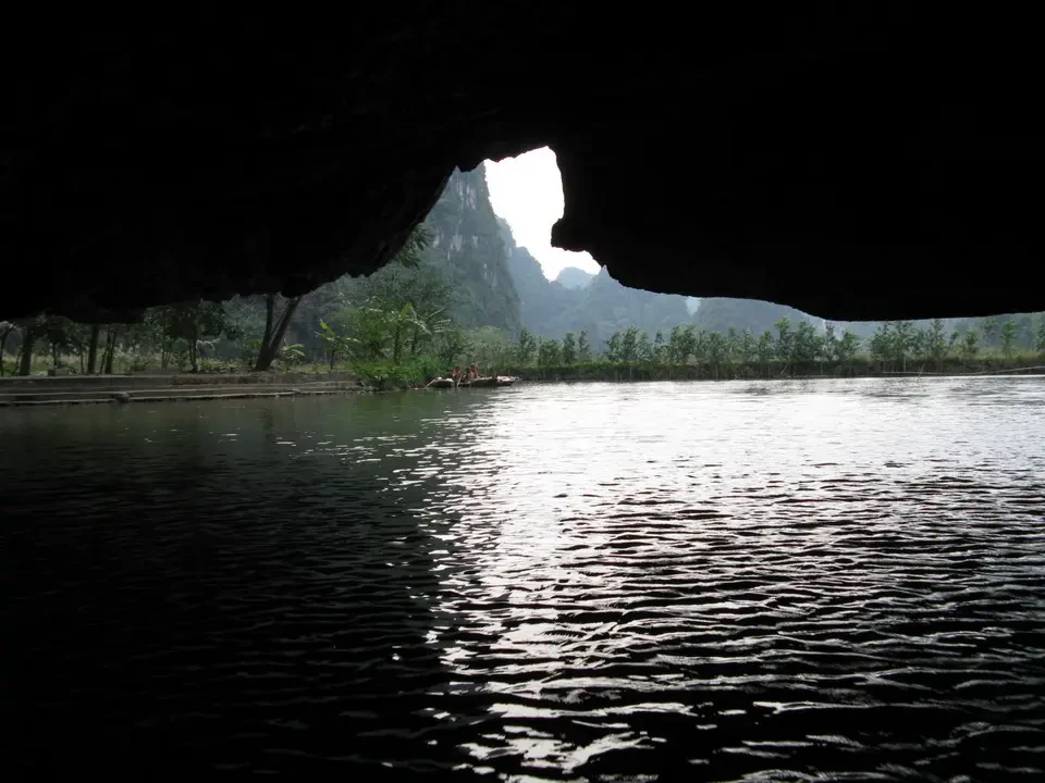 Paesaggio fluviale con montagne sullo sfondo attraverso una formazione rocciosa scura.