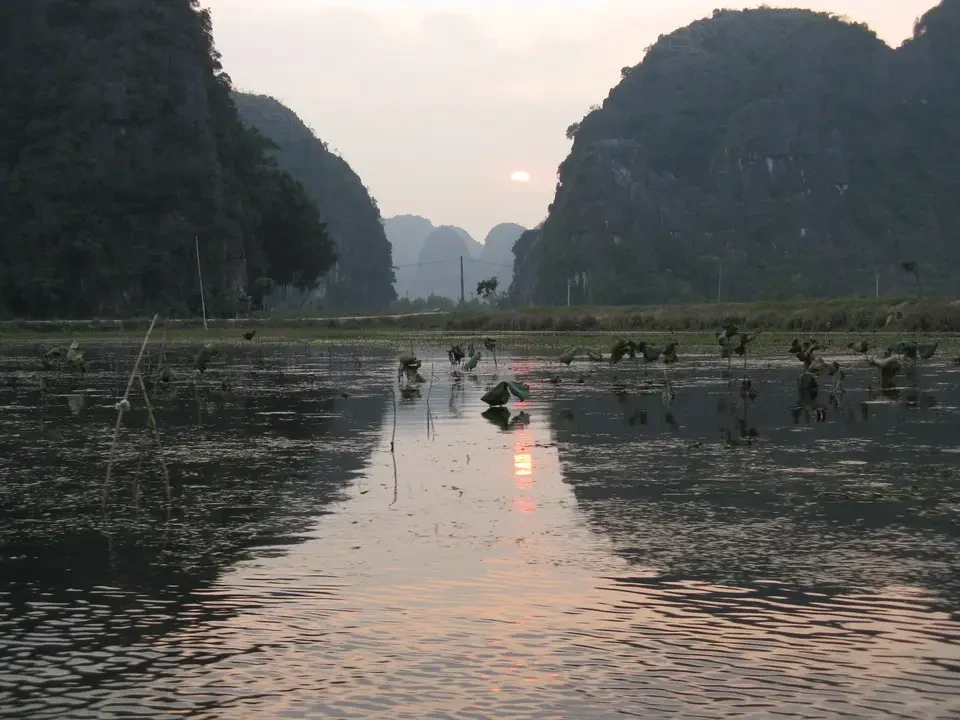 Paesaggio fluviale con montagne boscose riflettenti al tramonto in Vietnam o Cambogia.