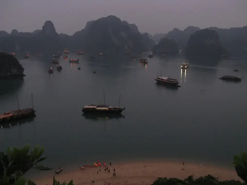 Paesaggio panoramico di Baia di Halong con isole verdi e barche in primo piano.