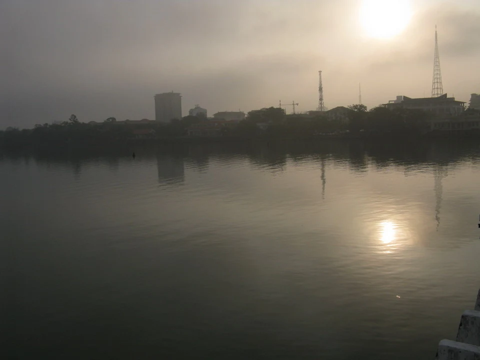 Paesaggio sfocato di una città riflessa sull'acqua al tramonto o all'alba.