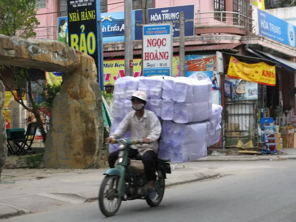 Un motociclista trasporta merci su una strada in Vietnam o Cambogia.