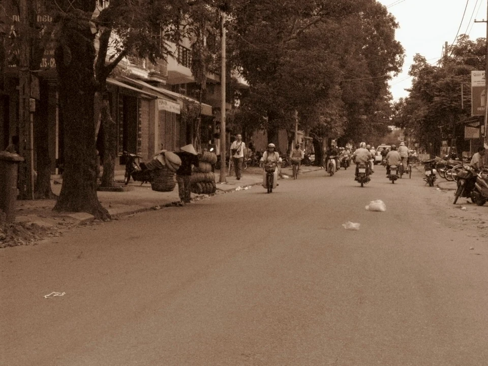 Una strada trafficata in una città del Vietnam o del Cambogia con persone e veicoli in movimento.