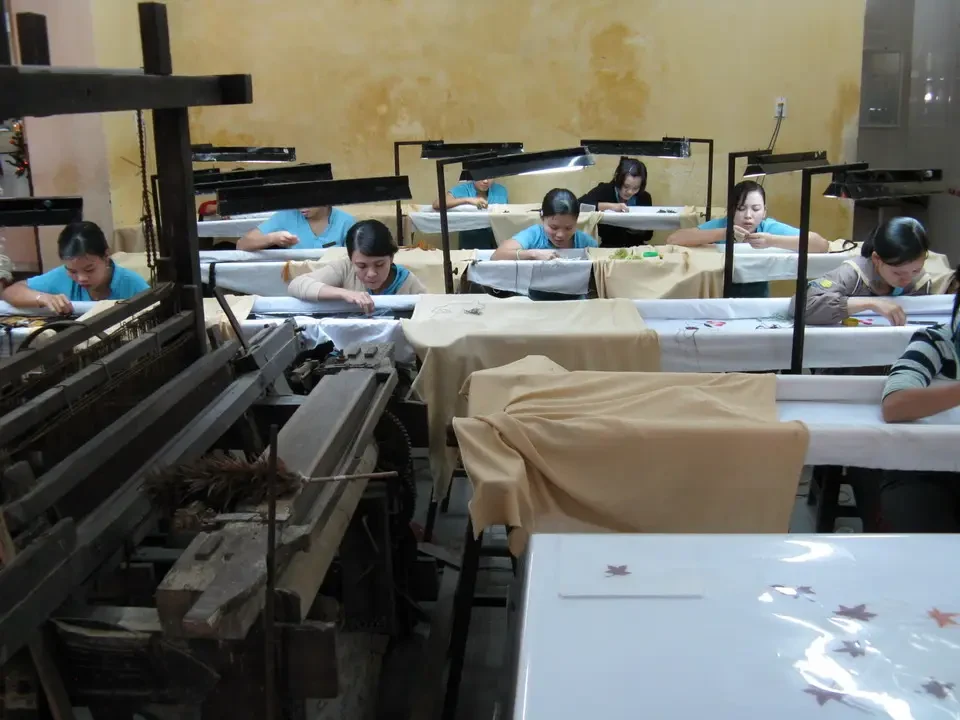 Artigiani lavorano su oggetti in un ambiente interno.