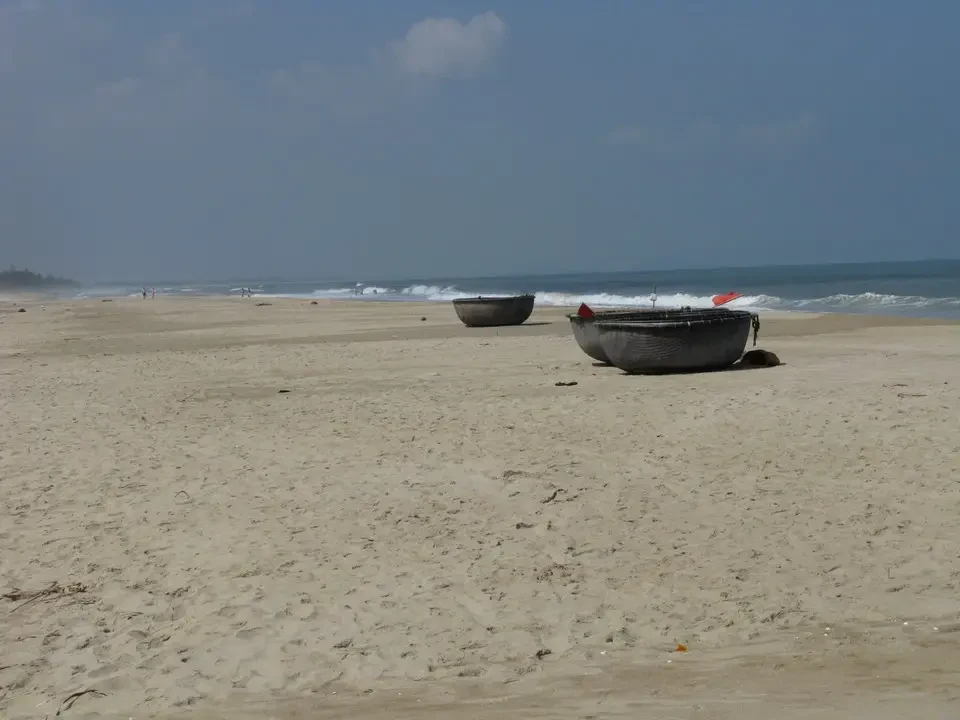 Una spiaggia sabbiosa con alcune barche ormeggiate all'alba in Vietnam o Cambogia.