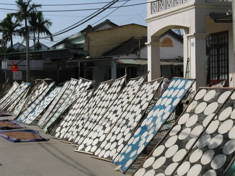 Una fila di pannelli decorativi a motivi bianchi e blu si estende lungo una strada in Vietnam o Cambogia.