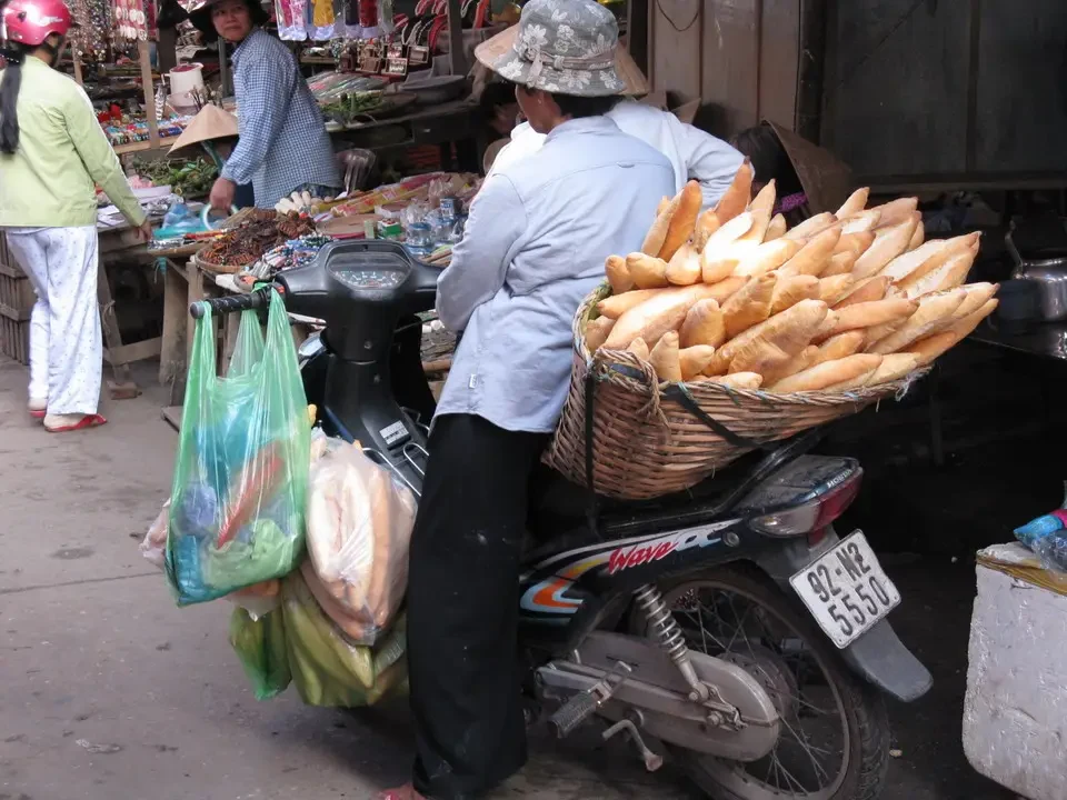 Venditori di pane e frutta all'aperto in un mercato vietnamita o cambogiano.