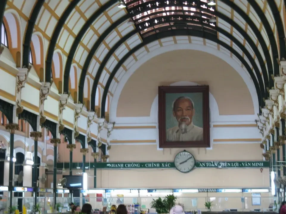 Vista interna della Posta Centrale di Saigon con archi decorati e ritratti di figure importanti.