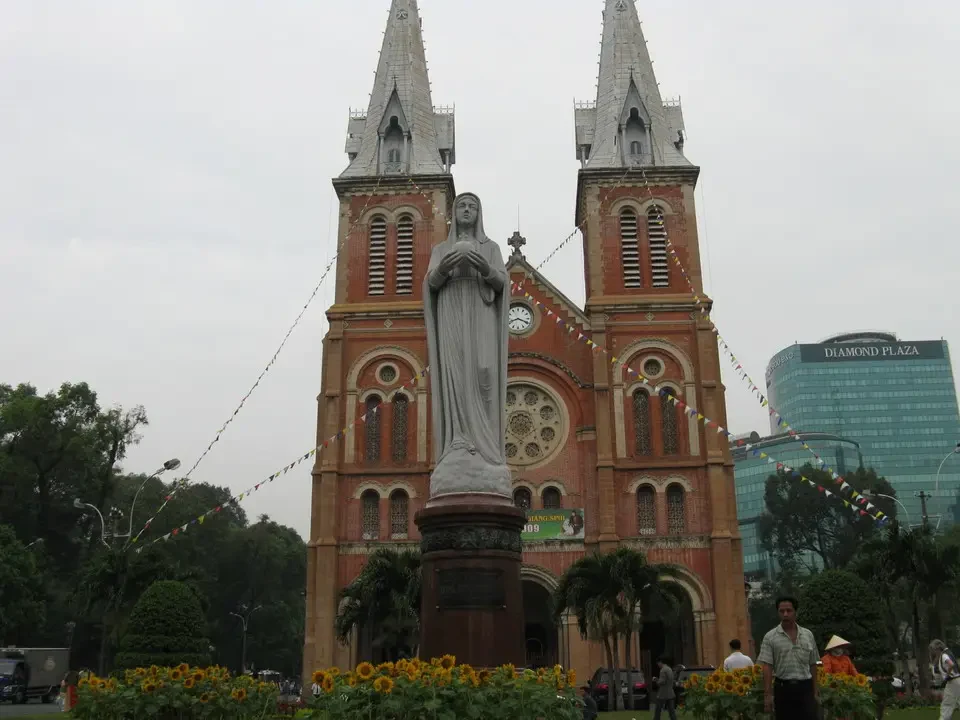 La Cattedrale di Notre-Dame a Saigon è visibile con una facciata in mattoni rossi e una statua centrale.