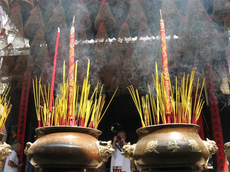 Candele accese adornano grandi strutture intrecciate davanti a vasi tradizionali.