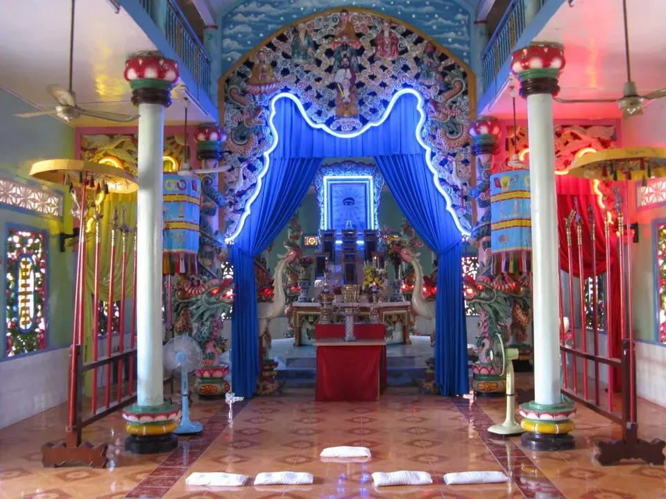 Interno decorato di un tempio in stile tradizionale vietnamita o cambogiano con colonne ornate.