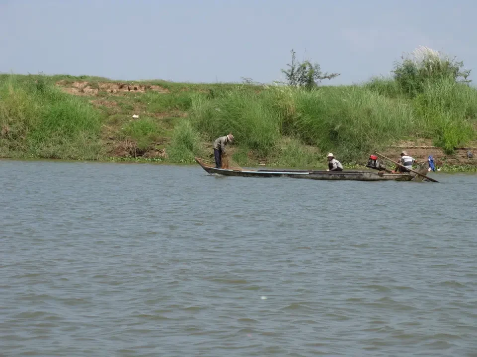 Una barca naviga sul fiume in un paesaggio rurale del Vietnam o del Cambogia.